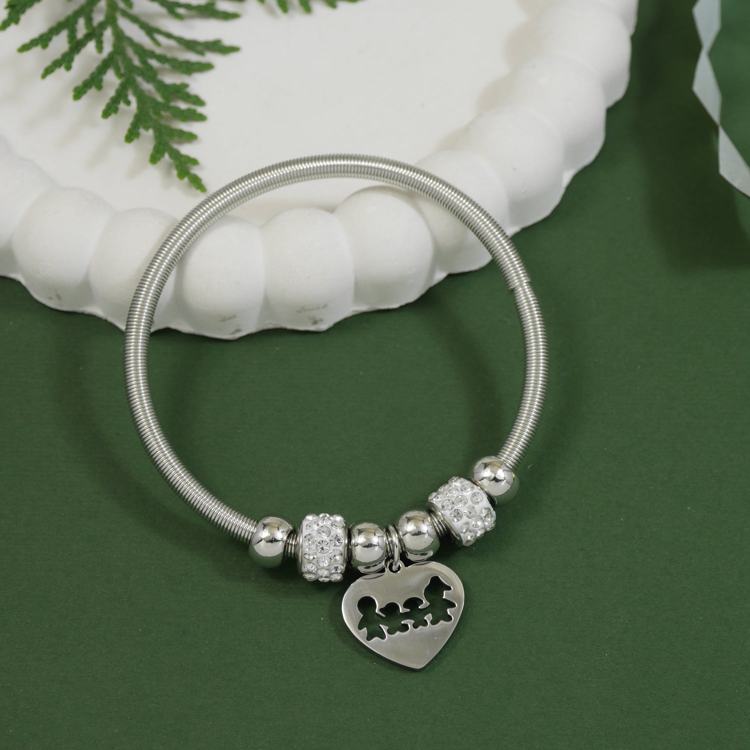 Silver charm bracelet with heart pendant featuring a family cutout and crystal-studded beads